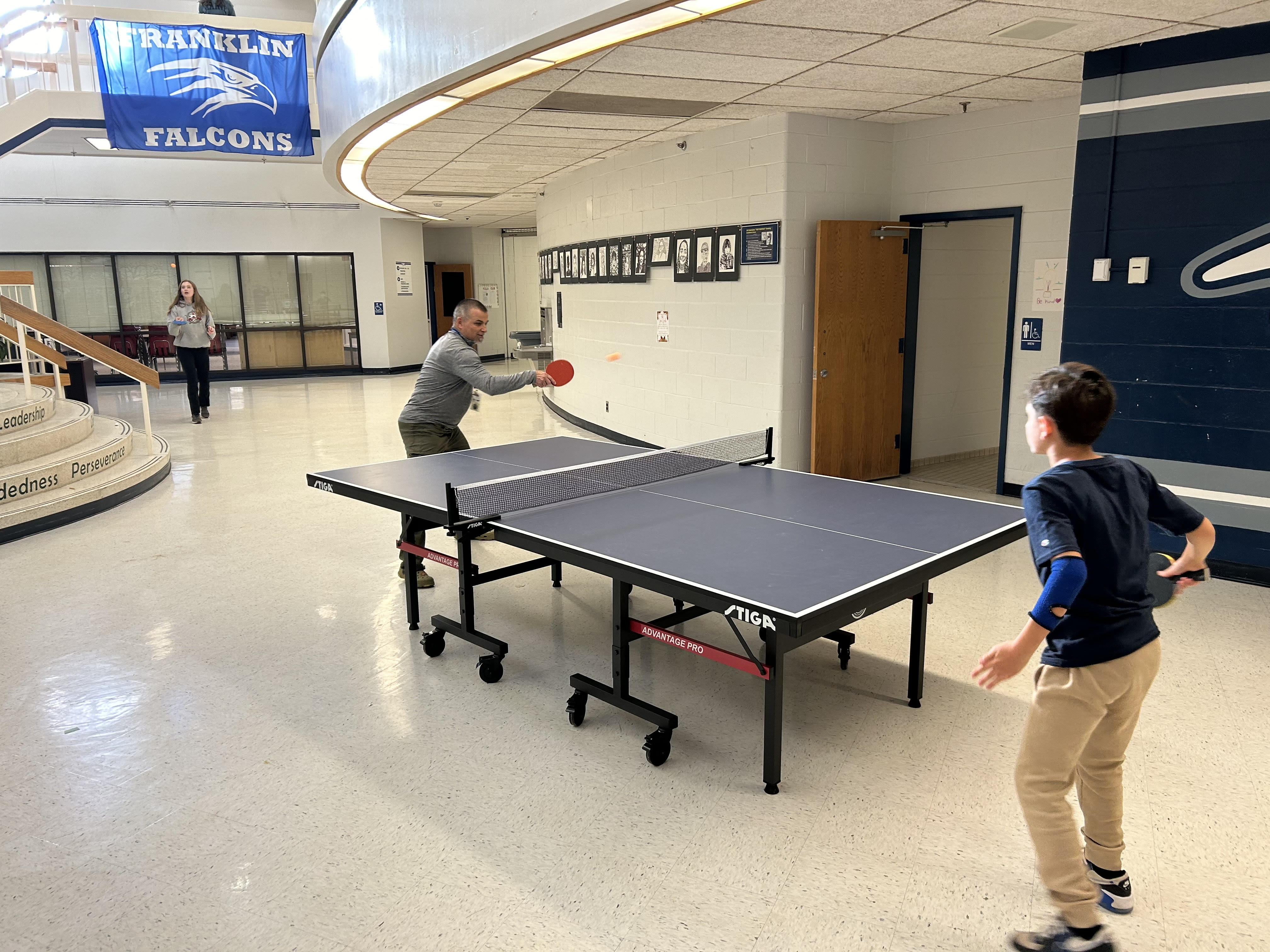 A teacher and student playing ping pong after school